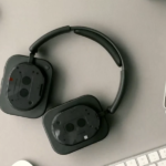 Side-profile view of the Nothing Headphone 1 over-ear headphones, featuring clear transparent earcups, silver aluminum hardware, and plush black ear cushions.